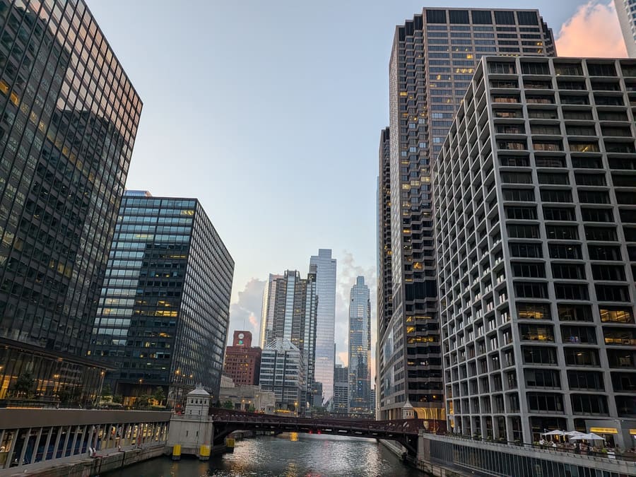 The Chicago River at dusk looking between downtown high-rises, a bascule bridge crossing in the foreground and the sky going pink behind the skyline
